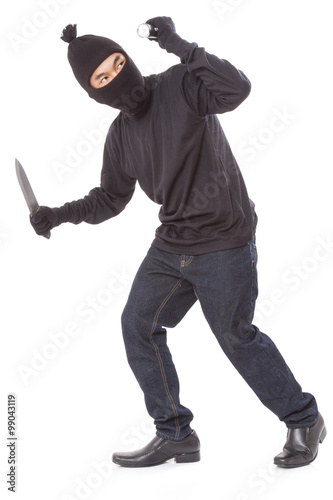 Thief in a mask holding flashlight with a knife on white background