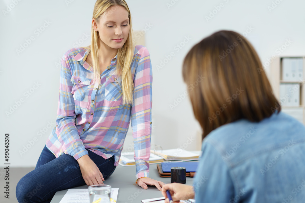 kolleginnen im büro unterhalten sich und schauen auf unterlagen kolleginnen im büro unterhalten sich und schauen auf unterlagen