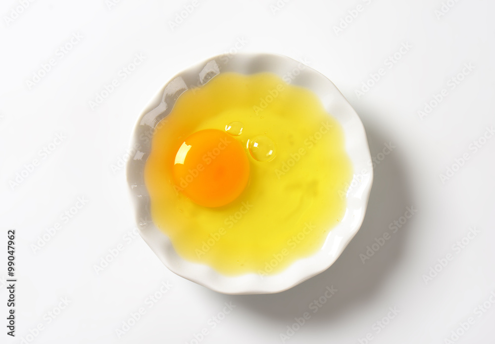 Raw egg white and yolk in bowl