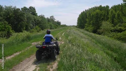 Young man driving quadbike in the forest.
