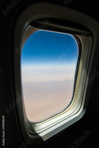 air travel concept looking out of airplane window to a clear blue sky