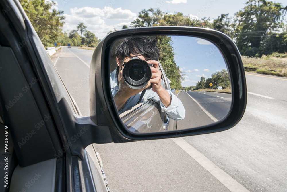 Reflection in side view mirror of young man with Dslr Camera driving car  over a Road side and nature background Stock Photo | Adobe Stock