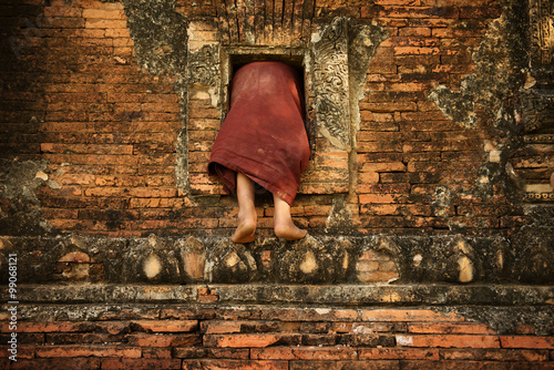 Canvas Print Buddhist novice monk climbing into monastery
