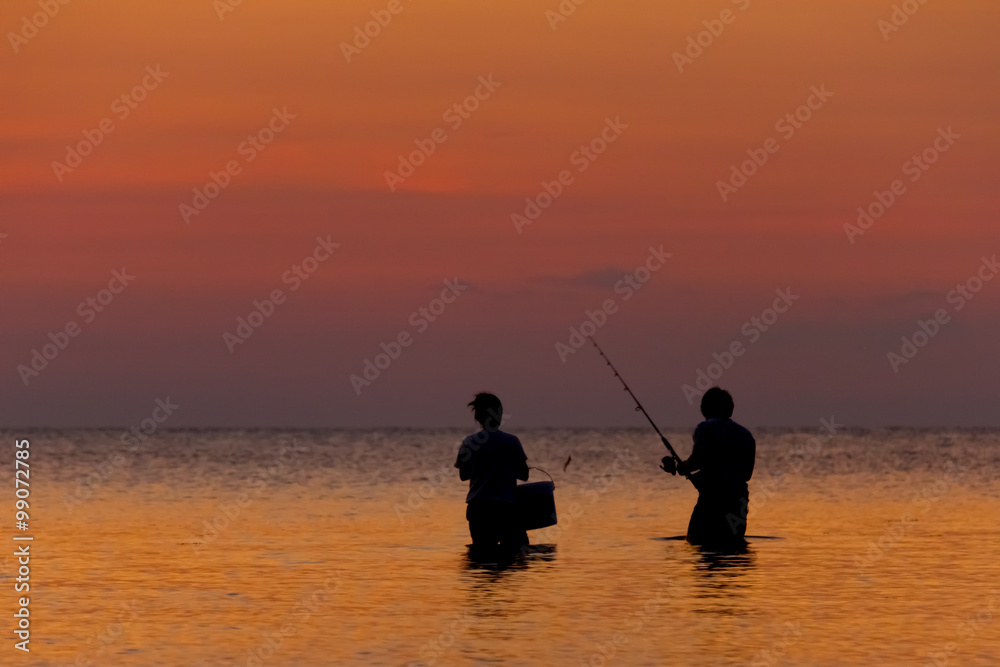 Two fisherman staying in the sea on a tropical island at the sunset 