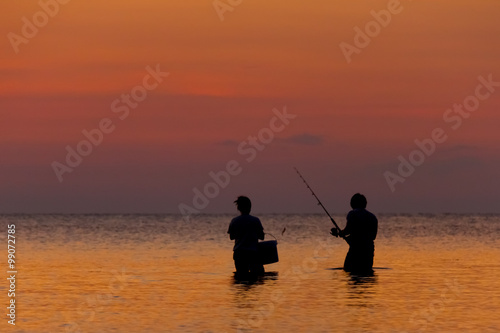 Two fisherman staying in the sea on a tropical island at the sunset 