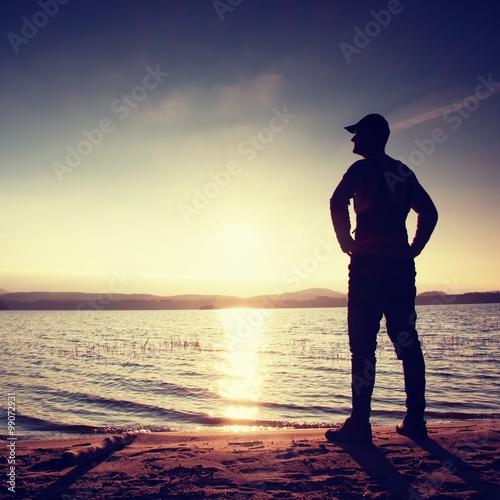 Silhouette of person in sportswear on beach seeing into morning Sun