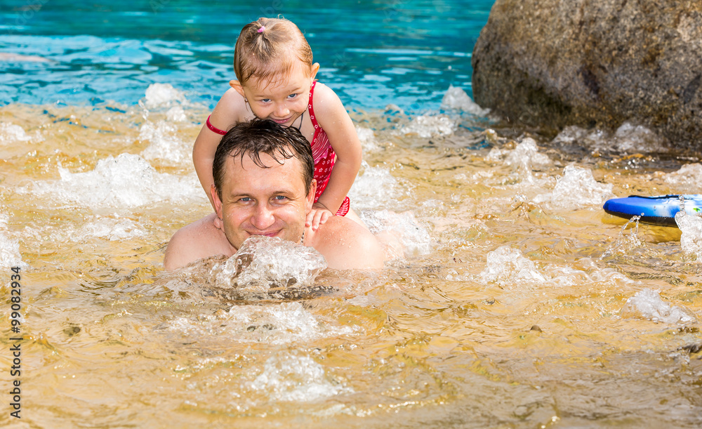 Active father teaching his toddler daughter to swim in pool on tropical resort. Summer vacations and sport concept Active father teaching his toddler daughter to swim in pool on tropical resort. Summer vacations and sport concept