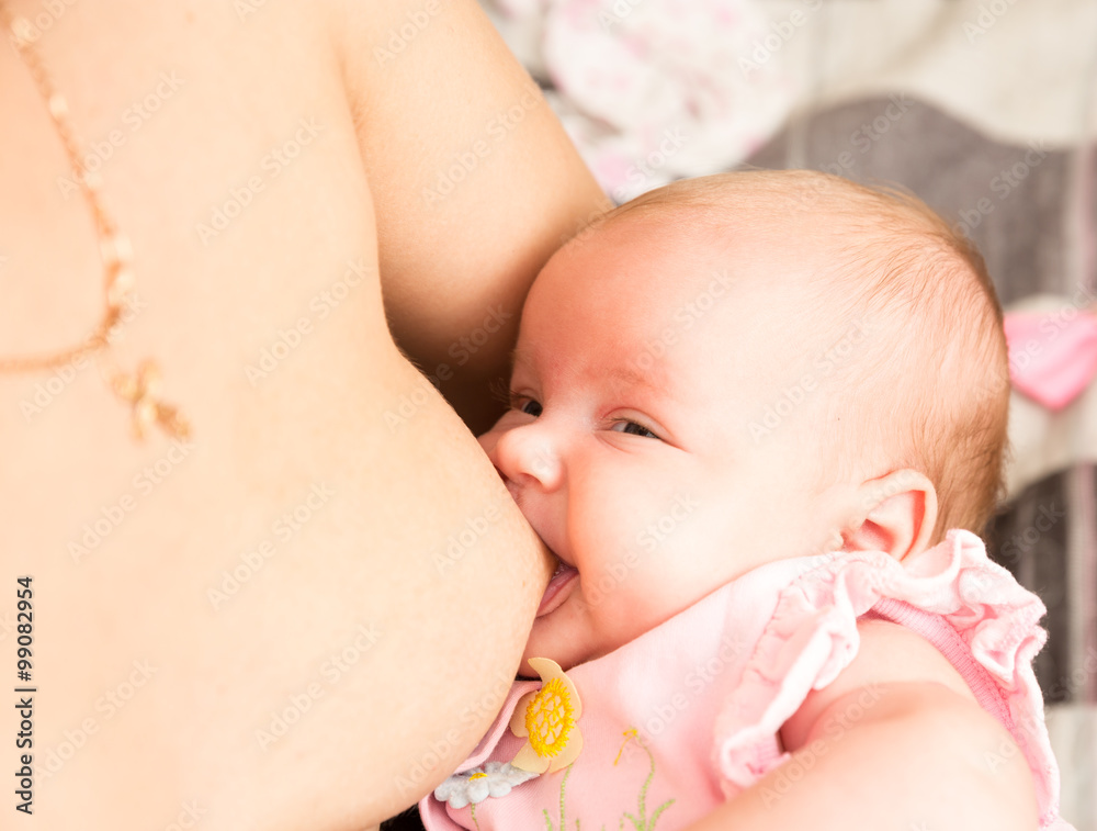Baby feeds on mother's breasts milk. Infant baby girl is suckling Baby feeds on mother's breasts milk. Infant baby girl is suckling