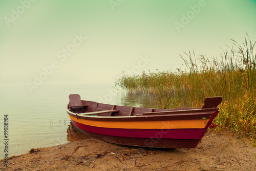 Autumn misty morning. Wooden boat on the river bank