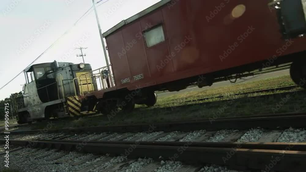 Diesel locomotive pulls off with a caboose attached on a railway line in the Mid West, USA. Wide view, low viewpoint with sun flare, in ultra high definition, 4K. Diesel locomotive pulls off with a caboose attached on a railway line in the Mid West, USA. Wide view, low viewpoint with sun flare, in ultra high definition, 4K.