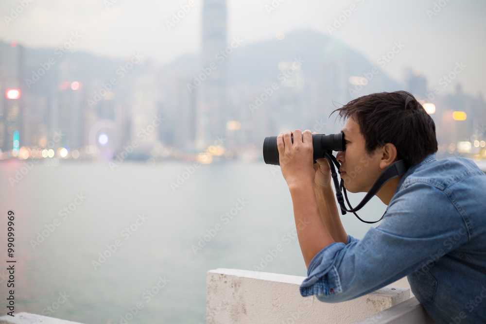 Asian Man looking though binoculars at Hong Kong