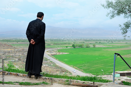 Canvastavla Armenian priest overlooking scenic fields and mountains