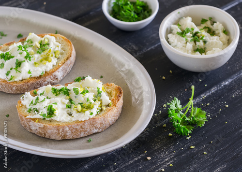sandwiches with ricotta cheese, olive oil, pistachios and herbs is a delicious and healthy Breakfast or snack, on an oval plate on a wooden surface