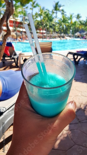 The taste of the good holiday. Blue cocktail in the glass near swimming pool.