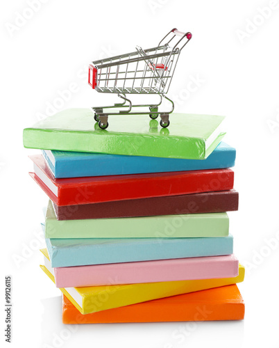 Stack of colorful books with small shopping cart isolated on white