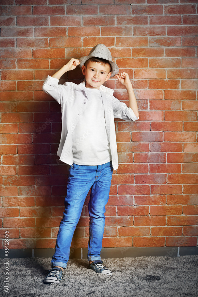Cute little boy on brick wall background. Kids fashion concept Cute little boy on brick wall background. Kids fashion concept