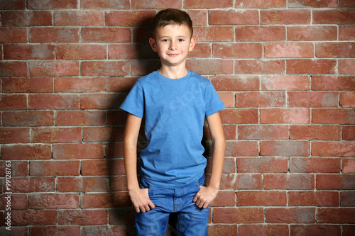 Cute little boy on brick wall background. Kids fashion concept © Africa Studio