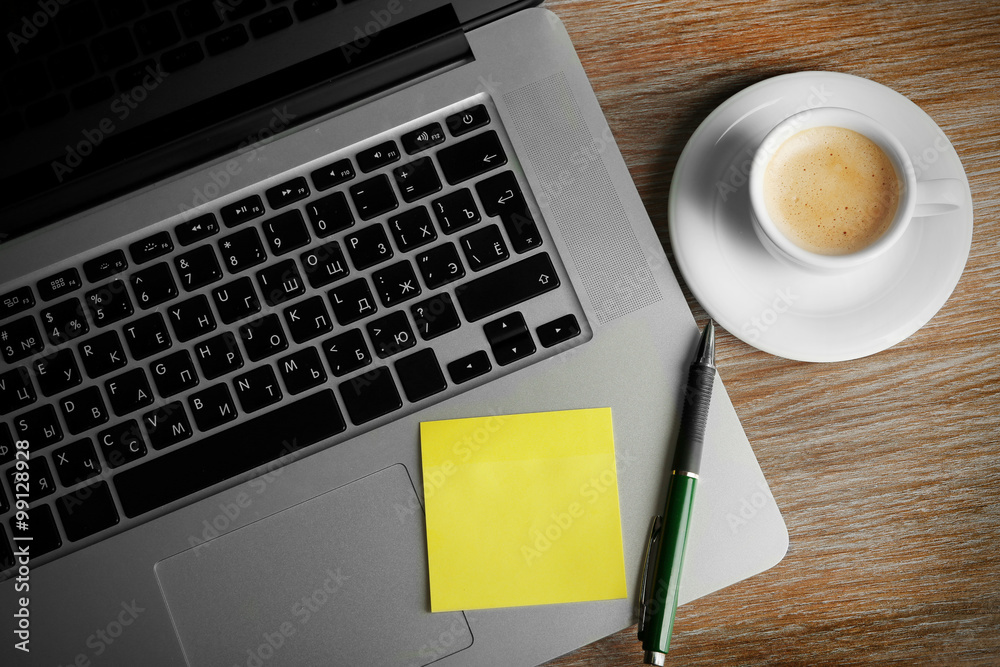 Empty yellow adhesive paper on laptop keyboard, pen and coffee cup on desk background Empty yellow adhesive paper on laptop keyboard, pen and coffee cup on desk background