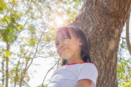 Close up happy adorable asian children climbing trees with sun flare.