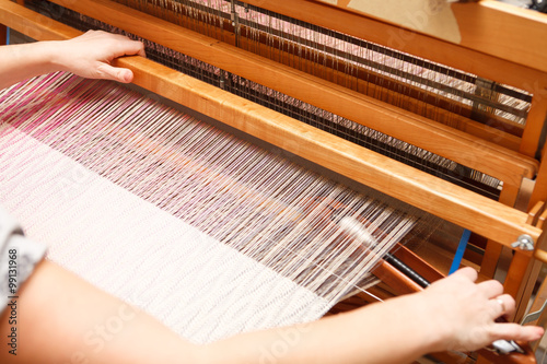 Hands of a woman who weaves on a loom