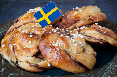 Traditional Swedish cinnamon buns served on a rustic plate. A very popular snack throughout Scandinavia known as Fika when taken with a cup of coffee.