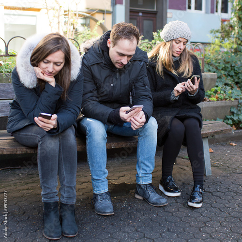 Drei Freunde am Smartphone draußen im Winter © Adam Gregor