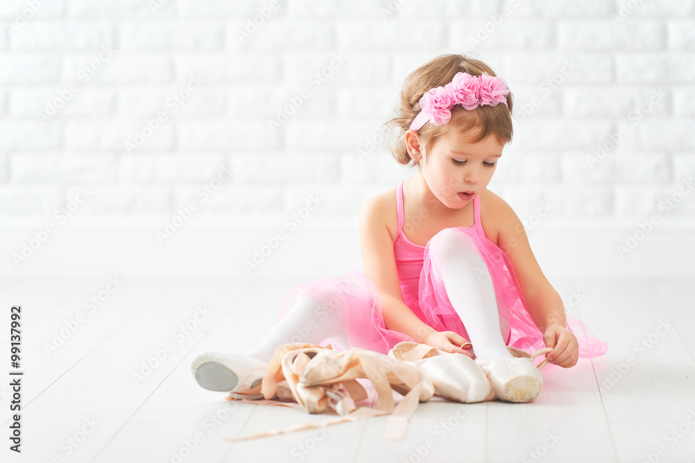 Fototapeta premium little child girl dreams of becoming ballerina with ballet shoe