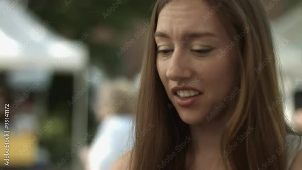 Close up of young woman looking at a cucumber at an open-air farmers' market. Close up of young woman looking at a cucumber at an open-air farmers' market.