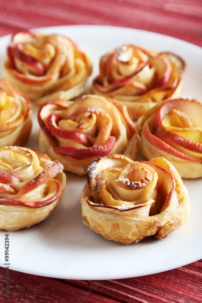 Fresh puff pastry with apple shaped roses on red wooden table