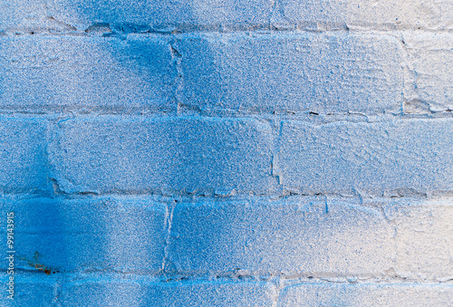 Closeup of white brick wall with blue spray stains