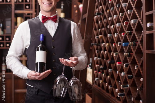Vászonkép Skillful young sommelier is serving a customer