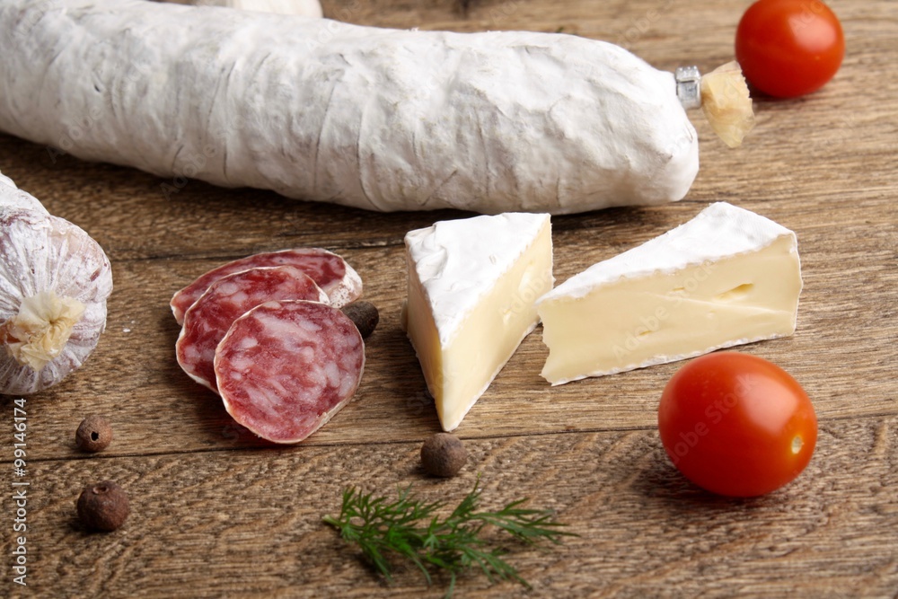 Traditional sliced salami on wooden board with brie Camembert Traditional sliced salami on wooden board with brie Camembert