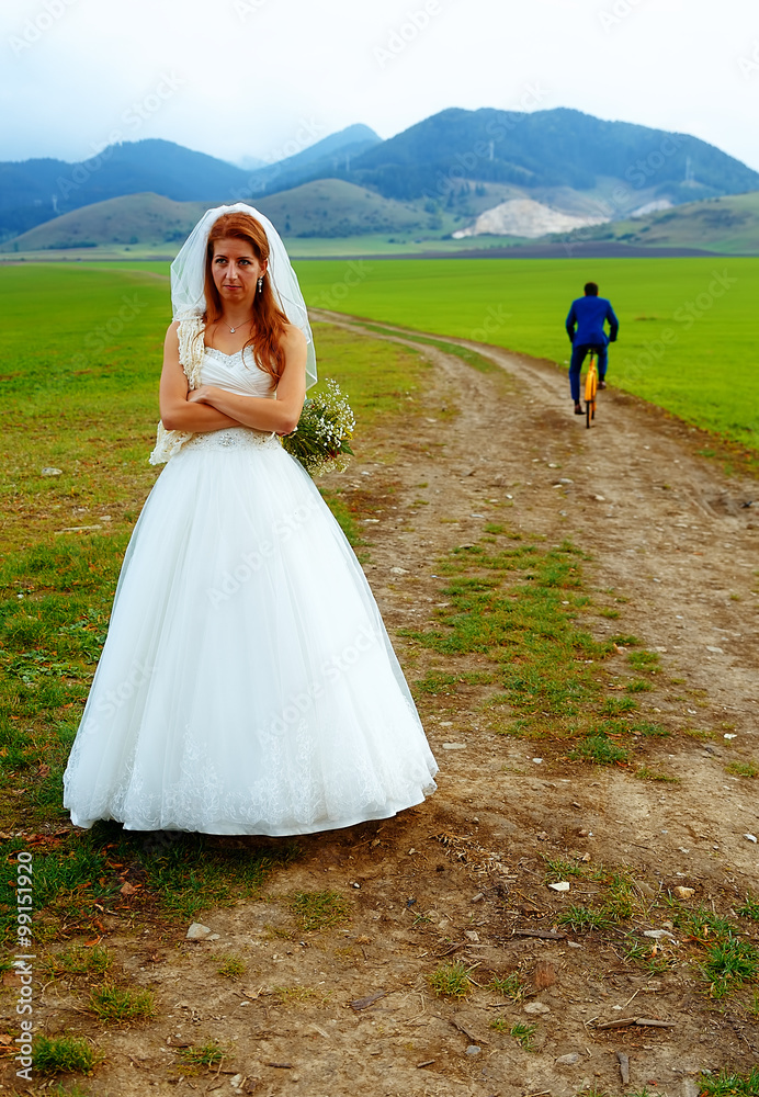 abandoned bride and groom running away on a bike - funny wedding concept.