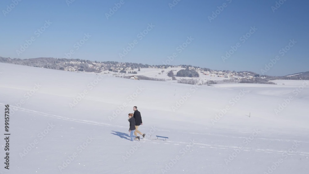 Aerial view on young couple enjoy walking on the snow during calm sunny winter day.
Aerial view on young couple enjoy walking on the snow during calm sunny winter day.
