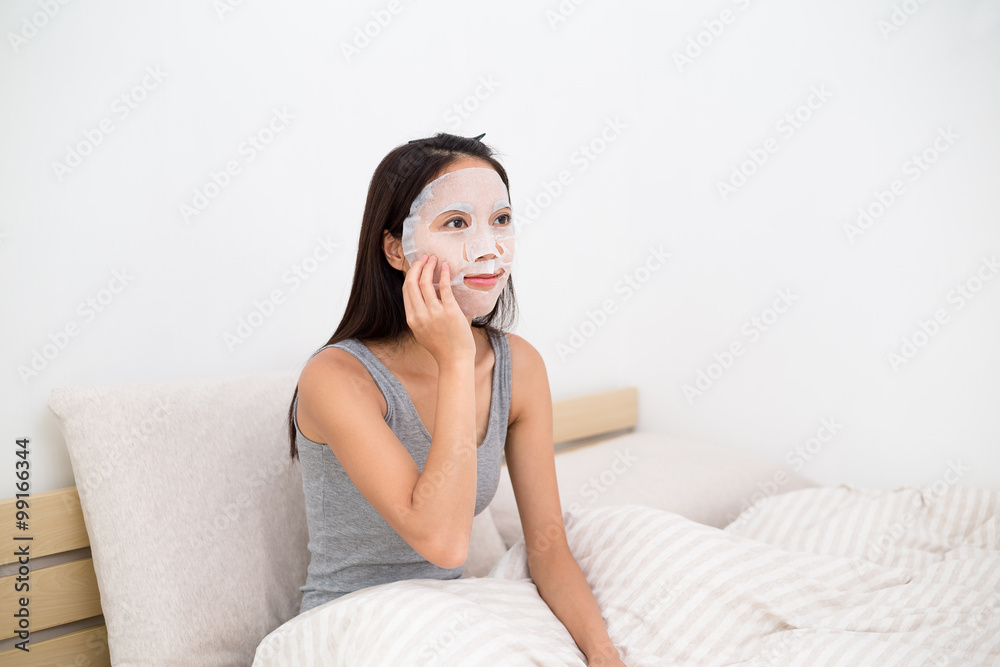 Young asian woman use of the facial mask on bed Young asian woman use of the facial mask on bed