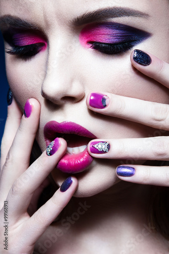 Beautiful girl with bright creative fashion makeup and colorful nail polish. Art beauty design