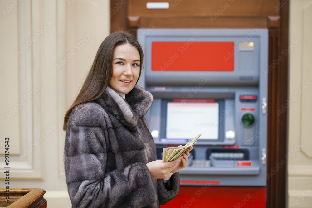 Woman hand showing dollar banknotes in front of the atm