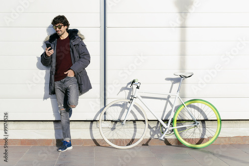 Handsome young man with mobile phone and fixed gear bicycle. © santypan