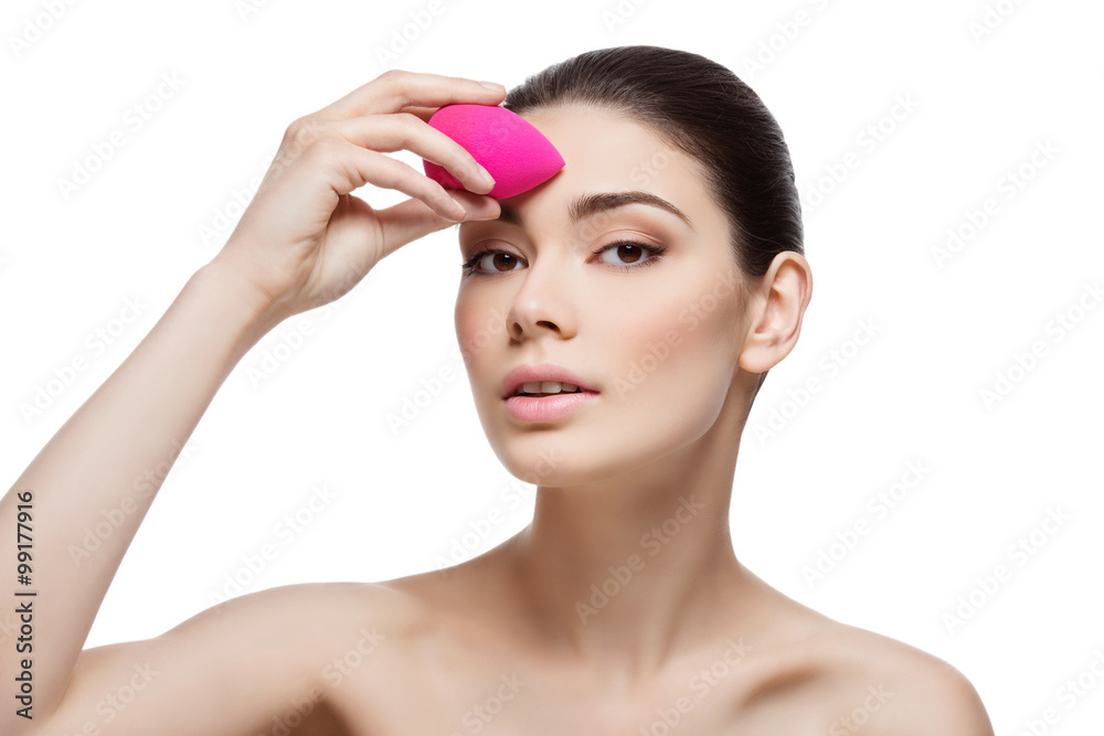 Beautiful girl applying foundation with sponge