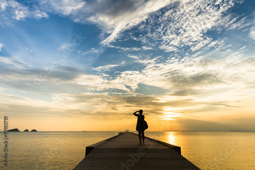 Woman standing on the pier and sunset photographs on a tropical island. Koh Samui, Thailand