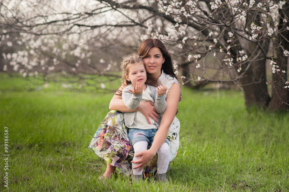 Mom kisses and hugs daughter on nature, family, motherhood, child Mom kisses and hugs daughter on nature, family, motherhood, child