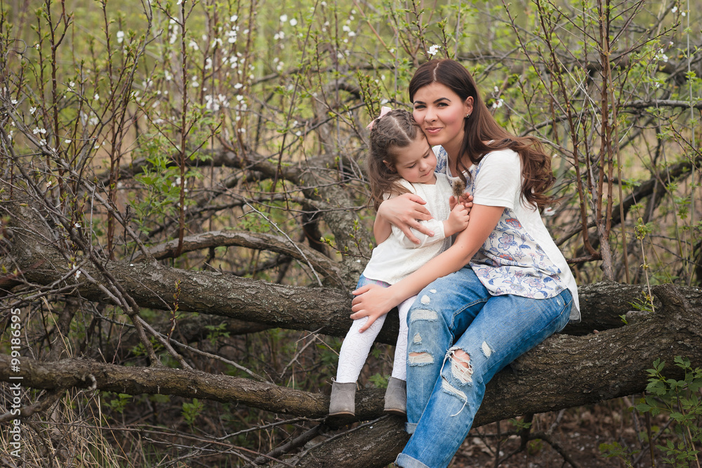 Mom kisses and hugs daughter on nature, family, motherhood, child Mom kisses and hugs daughter on nature, family, motherhood, child