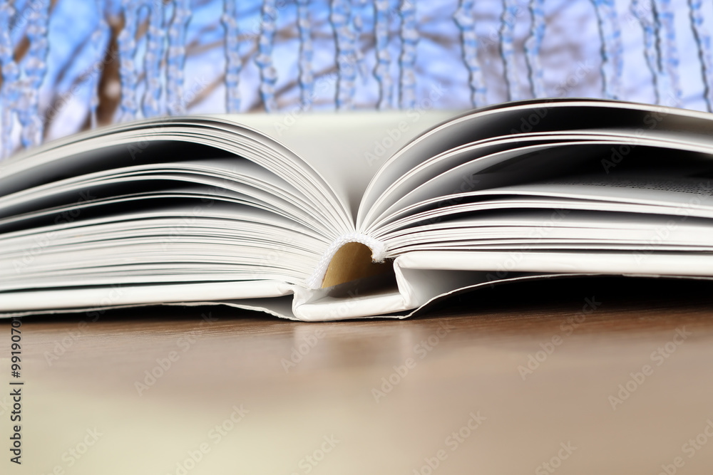Fototapeta premium Open book on a wood table over blue winter light background