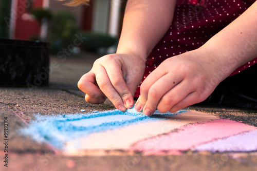 Kid playing with colored chalk on the sidewalk.
Nice colors in the golden hour. Close up of the hands.