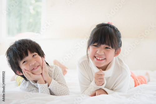 asian children lying on white bed