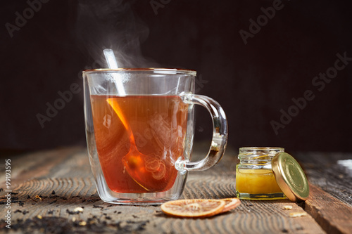 Steaming tea and honey on a wooden table