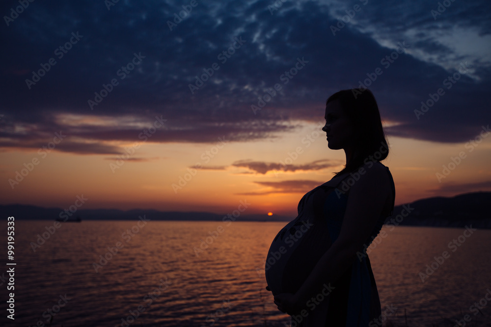 silhouette of a pregnant woman at sunset on the sea