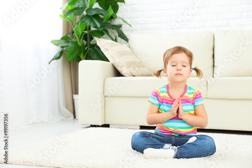 child little girl meditates in lotus position and practices yoga