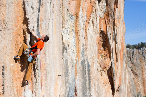 Slika na platnu Young male climber hanging by a cliff.