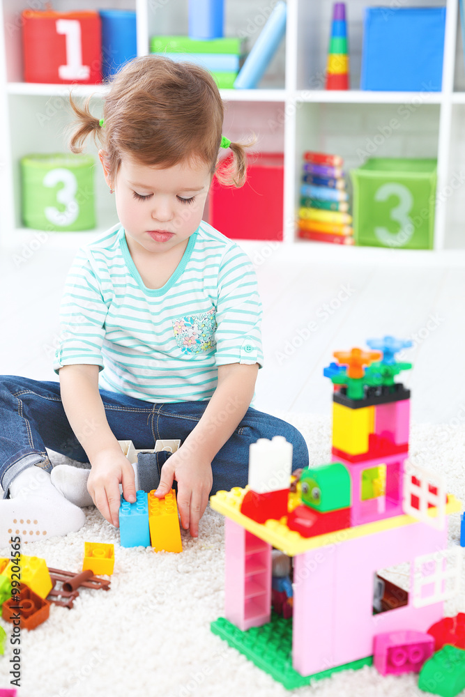 child girl playing with toys and builds constructor